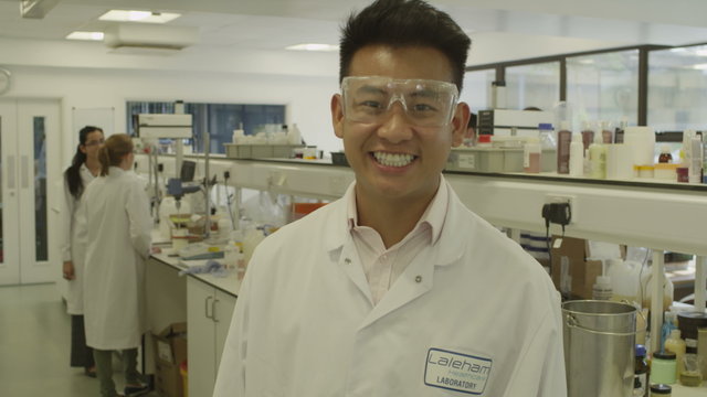 Portrait of young Asian scientist with science team in lab