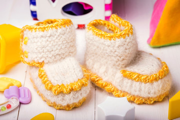 Booties for babies handmade surrounded by toys, closeup