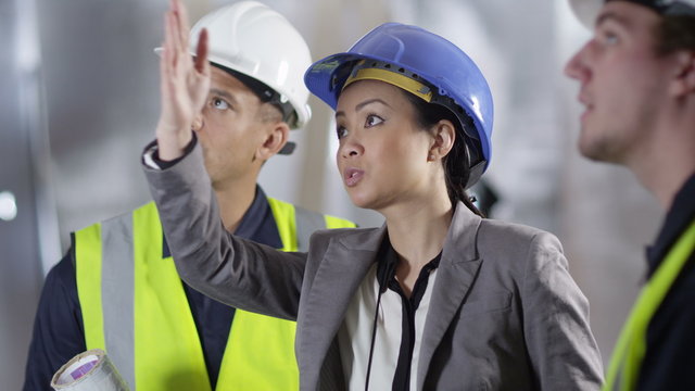  Confident female engineer or architect discussing construction issues with male colleagues. 