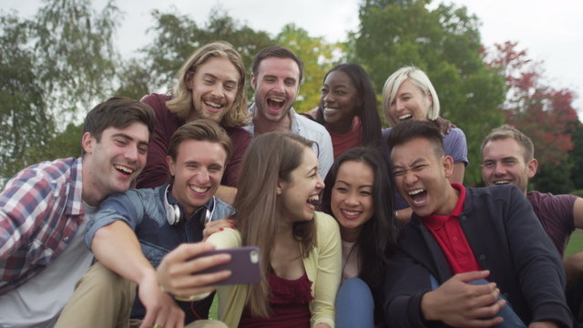  Happy group of friends in natural setting, pose for photo with mobile phone