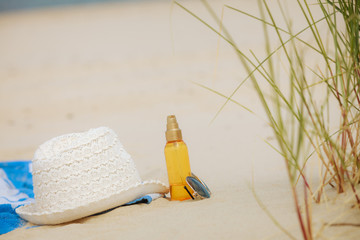 Beach set hat and sunscreen lotion lying on sand