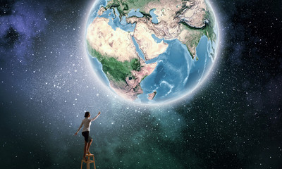 Obraz na płótnie Canvas Businesswoman reaching Earth planet 