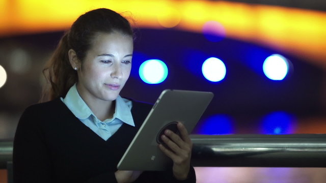 Attractive professional woman using computer tablet in the city at night