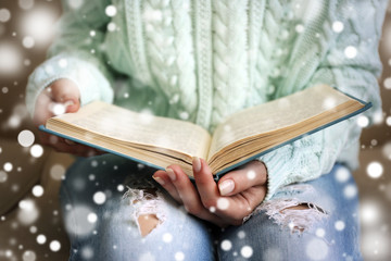 Woman reading book on sofa over snow effect