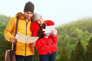 Happy couple with map and tablet on nature background