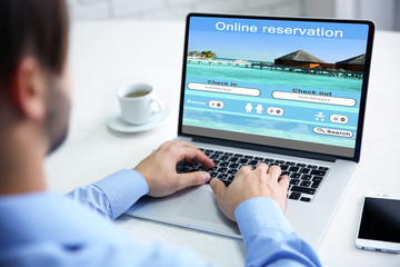 Fototapeta na wymiar Man using laptop to book hotel online