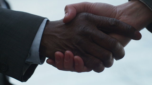  Close up on hands of 2 businessmen shaking hands outside city building. Shot on RED Epic.