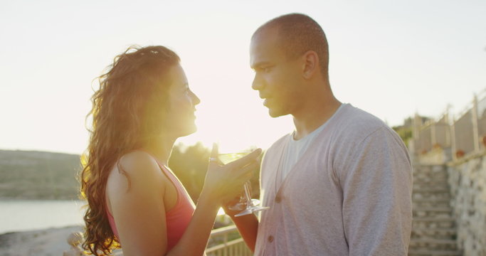 Happy romantic couple drinking wine at outdoor bar or restaurant beside the sea. 