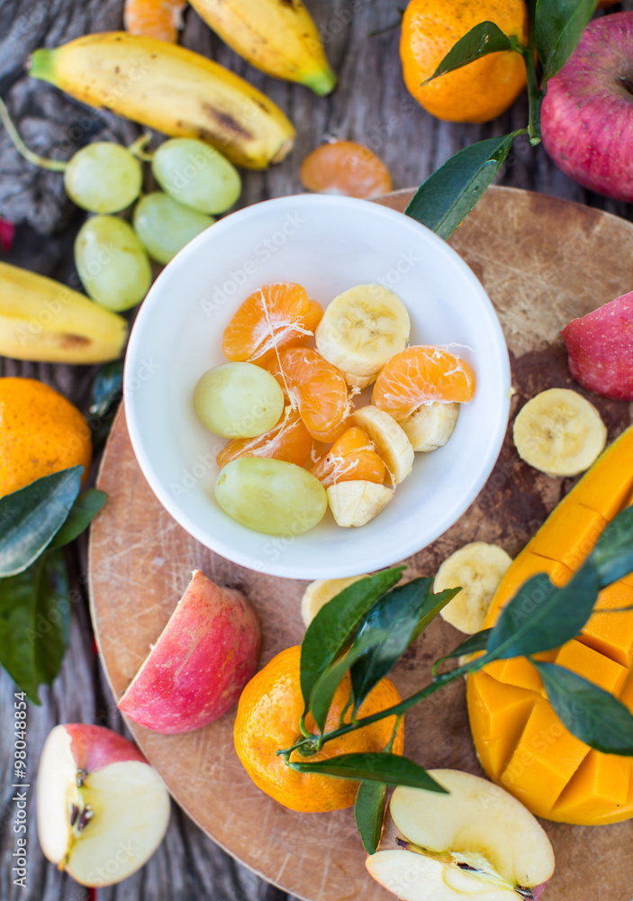 Wall mural Apples, tangerines, bananas, mangoes and grapes on a wooden boar