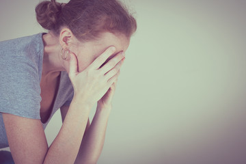 one sad woman sitting near a wall