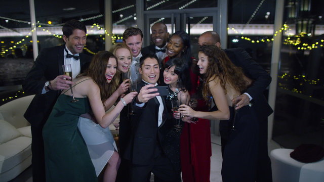 Happy attractive group of friends at a party pose to take a selfie together