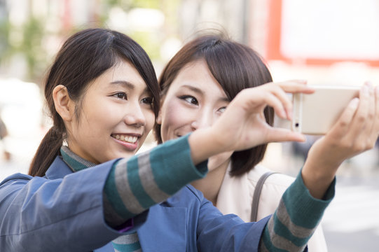 Two women are taking pictures in the smartphone
