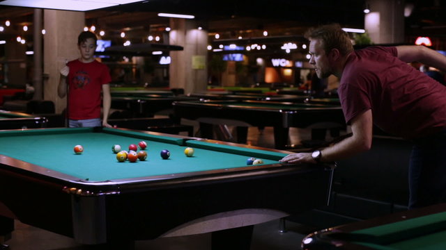 Father and son playing in pocket billiards