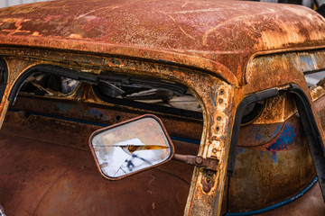 Detail of the wreckage side mirror of an rusty car in garage