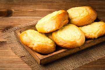 Yeast buns with cheese, traditional russian pastry, on the wooden background.