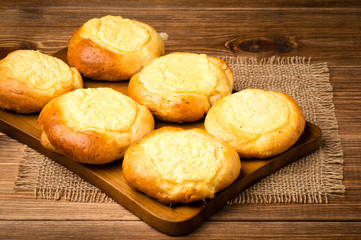 Yeast buns with cheese, traditional russian pastry, on the wooden background.