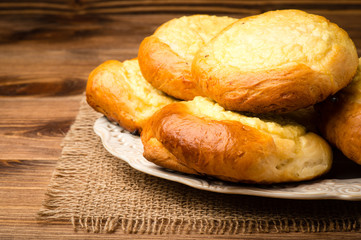 Yeast buns with cheese, traditional russian pastry, on the wooden background.