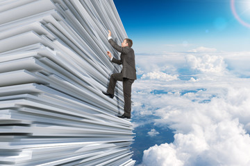 Businessman climbing up a huge stack of paper