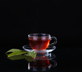 Glass cup of tea on black background.