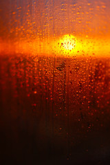 Fototapeta na wymiar Water drops on a window glass after the rain. The sky with clouds and sun on background.