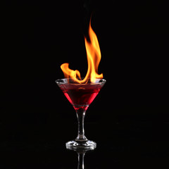 Burning alcoholic drinks with ice cubes, on black background