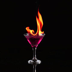 Burning alcoholic drinks with ice cubes, on black background