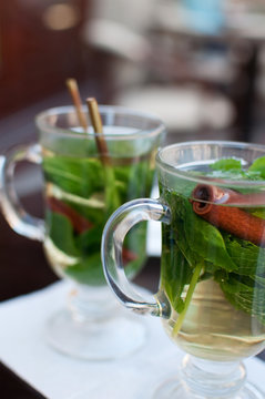 Glass cups of tea with cinnamon and mint leaves