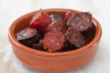 fried smoked sausages in ceramic bowl on white background