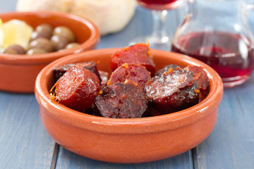 fried smoked sausages in ceramic bowl on blue background