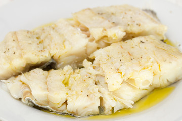 boiled cod fish with olive oil on plate