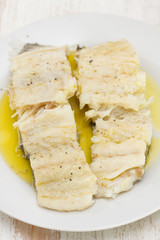 boiled cod fish with olive oil on white plate