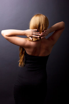 Beautiful female spin on a black background. Back pain. Cervical Spine. Beautiful Girl stands back.
