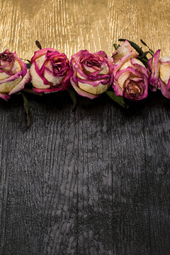 Dried Buds Of Pink Roses On A Black And Gold Board