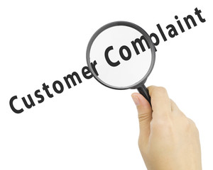 Magnifying glass with word CUSTOMER COMPLAINT in hand