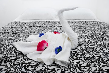 Towel swan with roses as a greeting on a apartment bed