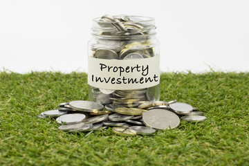 Coins in glass jar with property investment label, financial concept