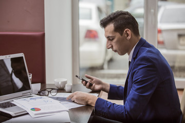 Бизнесмен во время работы читает сообщение в смартфоне
