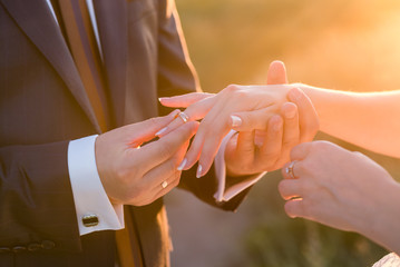 Groom slipping ring on finger of bride at wedding