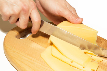 Close up of womans` hands cutting hard cheese with knife on cheese board isolated on white