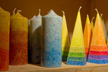 Rainbow Candles of Different Size Standing on Wooden Shelf
