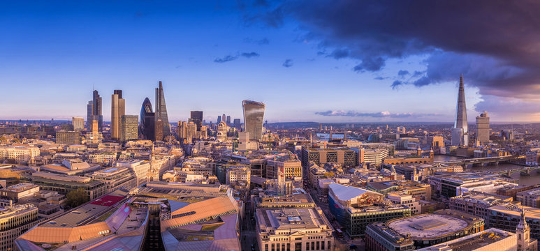 Panoramic skyline of the famous business district of London at sunset with dark clouds - London, UK