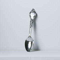 Vintage silver spoon on white glossy surface . 3D render