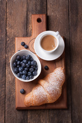 Croissant with coffee and blackberries on a wooden board. top view