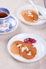 Pumpkin pancakes with honey, nuts and jam in a white plate on a table.