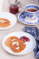 Pumpkin pancakes with honey, nuts and jam in a white plate on a table.