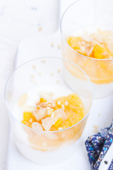 Sweet peach and pear compote with yogurt in a glass and jam on a white board. closeup.