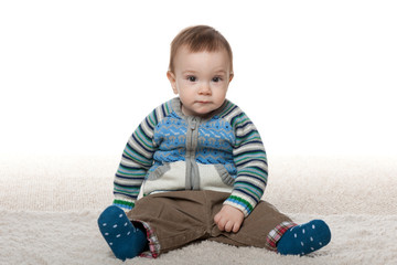 Fototapeta premium Fashion baby boy sit on the white carpet