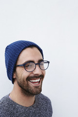 Young man laughing in knit hat and spectacles