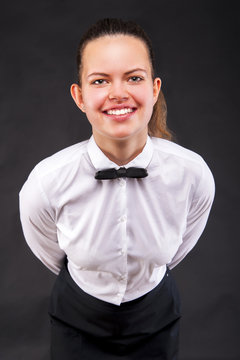 Young woman in waiter uniform over dark background.