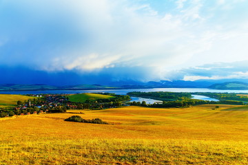 Beautiful landscape, green and yellow meadow and lake with village. Slovakia, Central Europe.